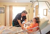 A hospice nurse attends to a female patient in bed