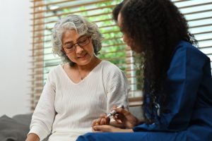 A diabetes nurse performing a finger prick test on a woman in the community